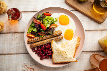 Portion of classic english breakfast with fried eggs, sausages and beans
