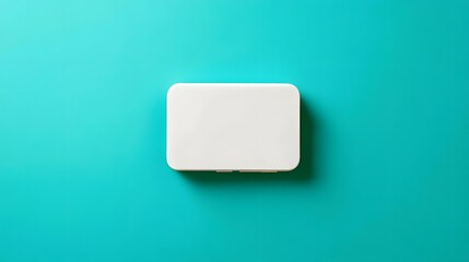 Minimalistic white plastic box on turquoise background, studio shot from above