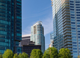 Skyscrapers and greenery create a vibrant cityscape on a clear day in downtown Vancouver with bright blue sky