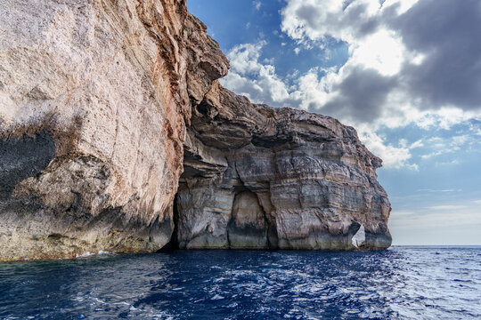 Sunlit Coastal Cliff with Sea Caves over Deep Blue Mediterranean