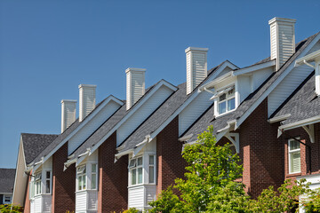 Row of charming residential homes with distinct chimneys under clear blue sky
