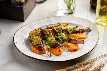 Three baked lamb chops with herb crust, served with vegetables and sauce