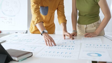 Professional business team members are reviewing financial data, analyzing charts and graphs, during a productive meeting in a modern office. Businesspeople concept