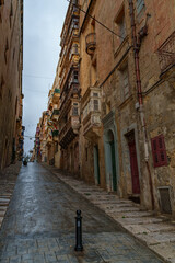 Steep Historic Street with Enclosed Wooden Balconies and Weathered Limestone Facades