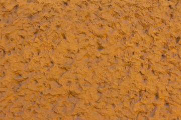 Earthy texture of a rustic wall showcasing rich orange tones and rough surface details