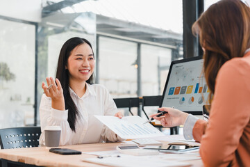 Young businesswoman smiling during meeting handing report to colleague in modern office, confident and engaged