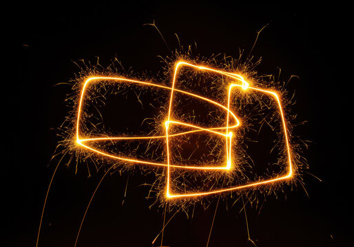 Intertwined golden light trails creating abstract geometric shapes sparkles