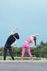 Two women stretching outdoors in activewear showing summer fitness routine and serene focus