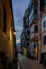 Blue-Hour Vertical Alley with Lantern Glow and Stacked Maltese Balconies