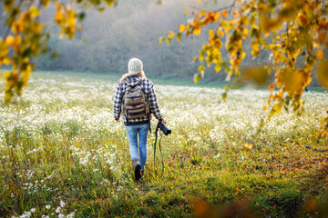 Woman photographer with camera walking through foggy autumn meadow. Walk and exploration outdoors