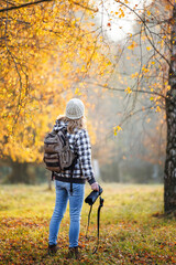 Photographer with camera exploring autumn forest. Woman is looking for outdoors adventure in fall season