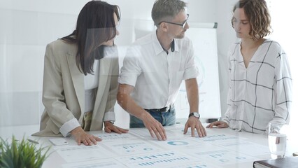 Professional team analyzing financial charts, colleagues reviewing data with focused expressions in modern workplace setting. Business people concept