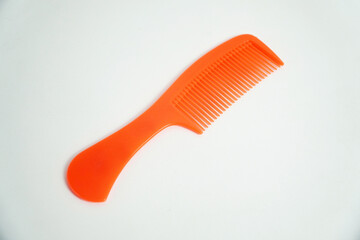 A bright orange plastic comb is isolated on a clean white background. Its vibrant color and simple design make it perfect for concepts of hair care, beauty, or grooming accessories.

