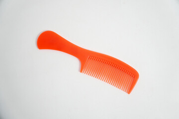 A bright orange plastic comb is isolated on a clean white background. Its vibrant color and simple design make it perfect for concepts of hair care, beauty, or grooming accessories.


