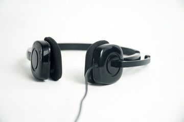 A pair of black on-ear headphones with a microphone boom, viewed from the top down on a white background. This image is perfect for concepts of a call center, customer service, communication, or music