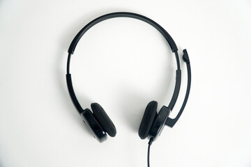 A pair of black on-ear headphones with a microphone boom, viewed from the top down on a white background. This image is perfect for concepts of a call center, customer service, communication, or music