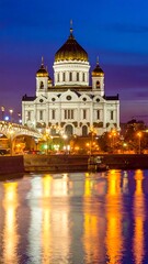 Fototapeta premium Majestic white cathedral with golden domes reflecting on river at twilight