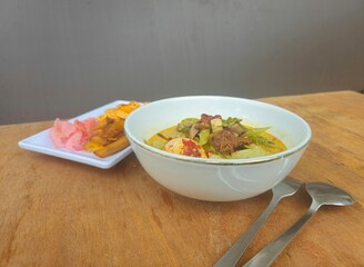 rice with vegetables Lontong sayur Padang from West Sumatra Indonesia is sliced lontong served with vegetables curry(jackfruit,chayote,beans,fern),boiled egg,fried tempeh,rendang,crackers and sambal