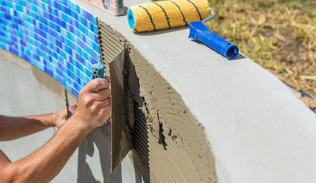 A man lays mosaic tiles in a swimming pool. Selective focus.
