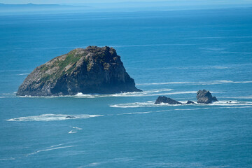 Crescent city , CA A scenic view of a rugged island surrounded by the vast expanse of the blue ocean, with smaller rock formations nearby.