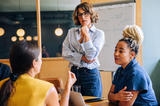 Three colleagues discussing ideas during a brainstorming session in the office - Powered by Adobe