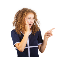 Side view surprised teenage girl with curly hairstyle, looking astonished as keeps mouth open, one hand on cheek and other pointing to something. Frizzy ginger adolescent on isolated background