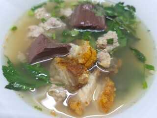Close-up of Tom Lued Moo, a traditional Thai-Chinese pork blood and offal soup with crispy pork, enjoyed as a popular local specialty.