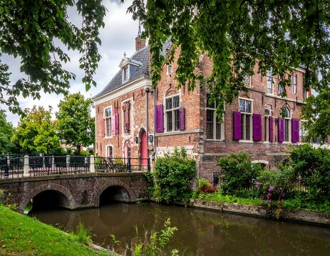 Historical brick building next to a canal with a small arched bridge