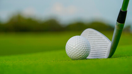 Golf clubs and balls on a green lawn in a beautiful golf course with morning sunshine.