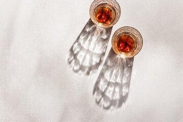 Whiskey Glasses with Shadows and sunlight Reflection on beige background,neutral photo minimal style, aesthetic top view summer still life, refraction throug crystal shine cups, caustics