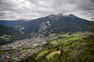 Landeck mountain panorama with Giggler Spitze, Seekopf, Gatschkopf and Thialkopf peaks under moody clouds and late‑summer greens; ideal for Tyrol travel and tourism ads.