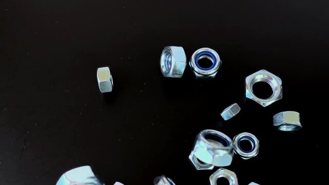 Metal hex nuts, fastening concept, industrial application, mechanical engineering context - various steel nuts with blue nylon inserts on black surface, illustrating construction hardware and precisio