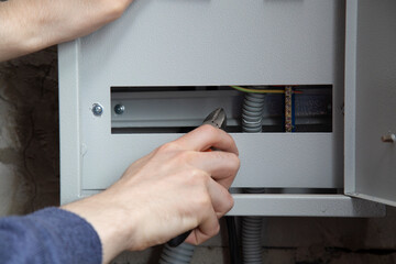 An electrician is installing wires on an electric meter
