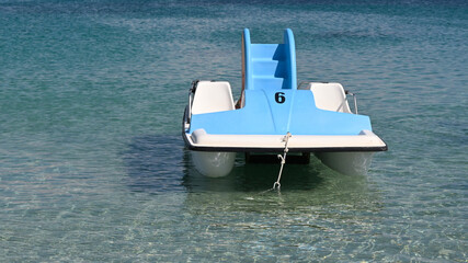 Pedal boats moored in the shallows of the sea water. Blue pedalo with 6 number