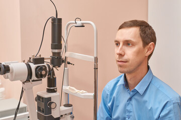 Caucasian male adult undergoing eye examination with medical equipment in clinic setting.