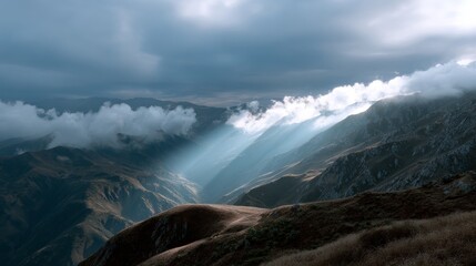 Sun rays illuminate majestic mountain range beneath dramatic cloudy sky
