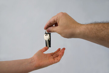 Mano de hombre entregando llavero con llaves a la mano de una mujer