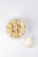 Fresh dumplings in clear container with sour cream side
