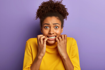 Young anxious woman showing worried expression with hands near face against vibrant purple backdrop. Generative AI.