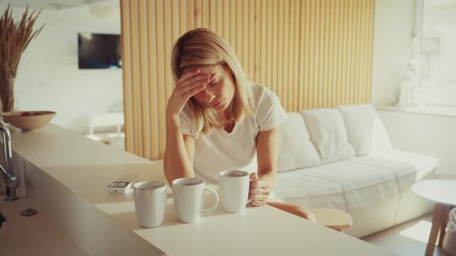 Woman Feeling Tired Sitting at Table with Coffee Cups
