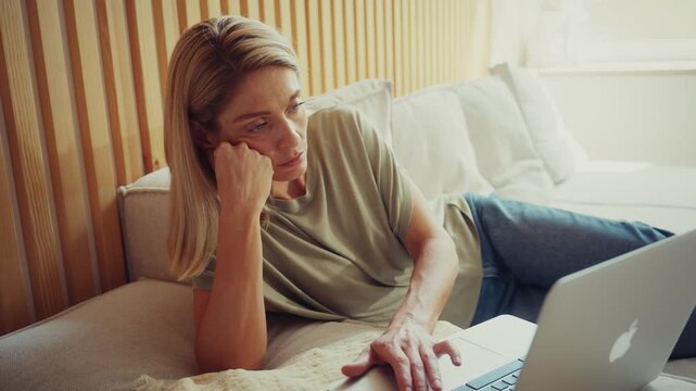 Unhappy Woman Using Laptop While Sitting on Sofa