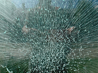Close-up of shattered glass with spiderweb-like cracks radiating from a central impact point. Ideal for backgrounds, design, or illustrating breakage and fragility.