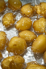 Whole Organic Raw Potatoes In Water Top View, Splash And Ripples.
