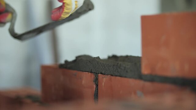 Mason applying mortar on red bricks with trowel