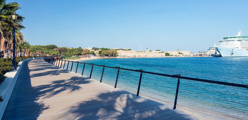 Coastal serenity unfolds along the palm lined promenade of Rhodes, where sunlight and sea breeze merge in peaceful Mediterranean escape with clear blue water and gentle motion. Greece