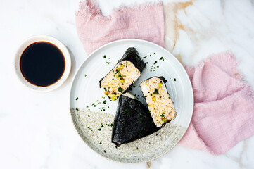 Japanese rice balls onigiri wrapped in nori seaweed served on a plate.