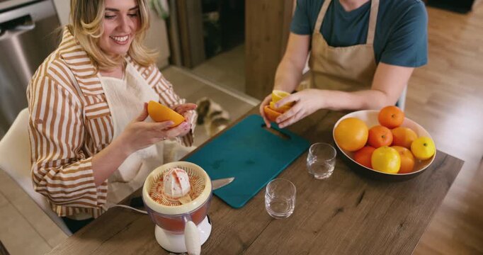 Couple makes fresh juice together in cozy kitchen with bright fruits and laughter