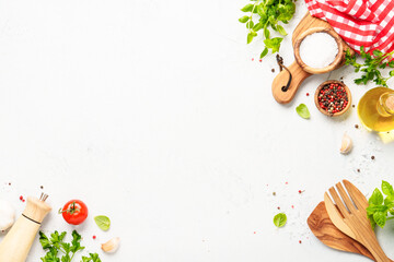 Spices, herbs and vegetables with olive oil on white kitchen table.