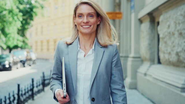 Confident Businesswoman Walking Outdoors Holding Laptop in City