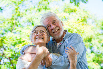 Beautiful cute couple of seniors hugged having fun and enjoying together outdoors in green park...